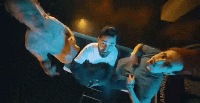 a group of men are sitting on a couch in a dark room and looking up at the camera .