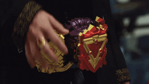 a person is holding a purple and gold item with a red triangle on it