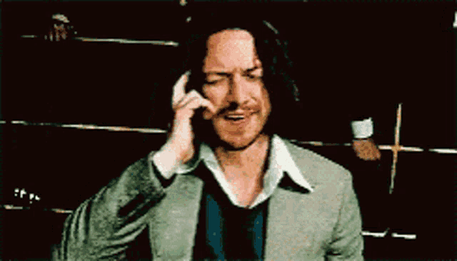 a man talking on a cell phone with a cross in the background