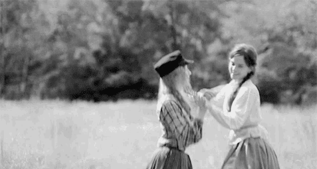 a black and white photo of two girls dancing in a field .