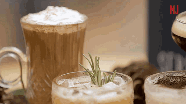 a glass with a rosemary sprig in it sits on a table