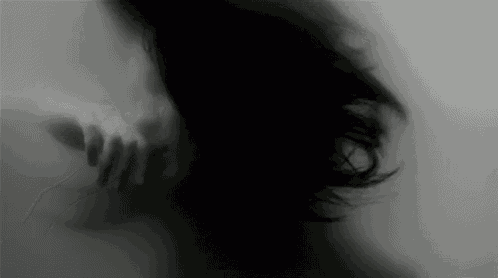 a blurry black and white photo of a woman 's face behind a glass wall .