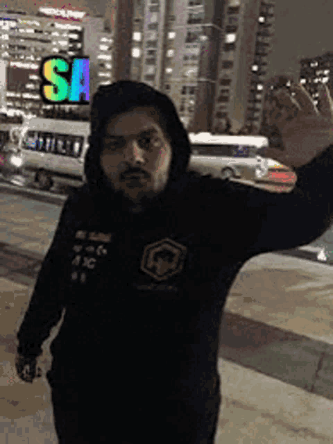 a man in a black hoodie is standing in front of a building with a sign that says sa