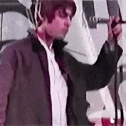 a man is singing into a microphone while wearing headphones and a jacket .