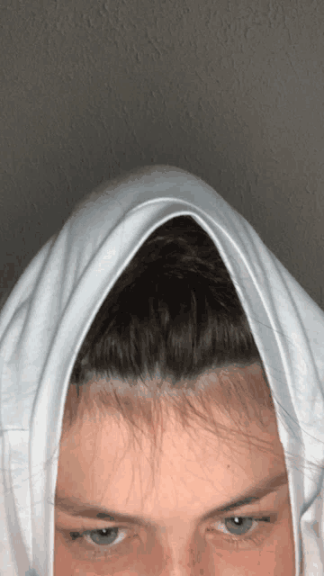 a close up of a person 's head with a white shirt covering it