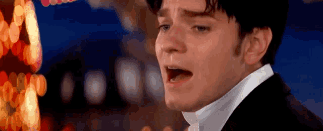a man in a tuxedo is singing into a microphone