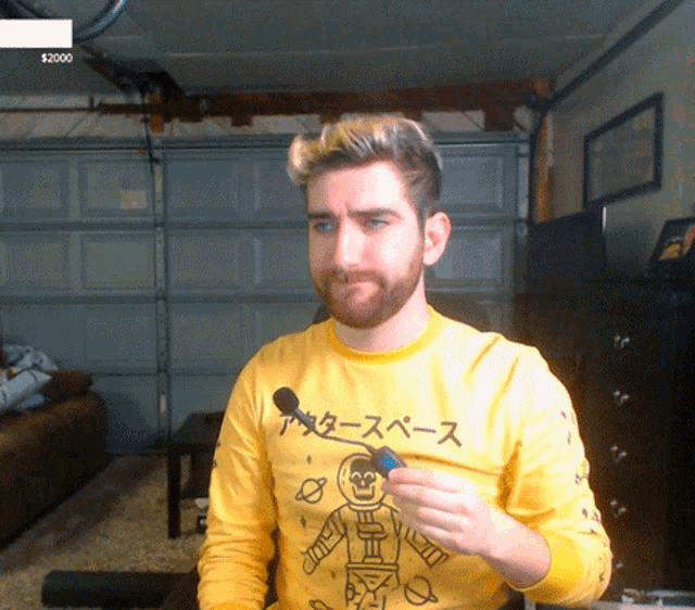 a man wearing a yellow shirt that says ' outer space ' on it is holding a blue object