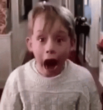 a young boy is making a surprised face while wearing a white sweater .