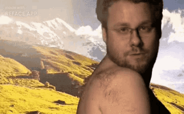 a man with glasses is standing in front of a mountain .