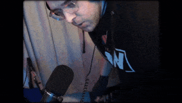 a man wearing a black shirt with the letter n on it is standing in front of a microphone