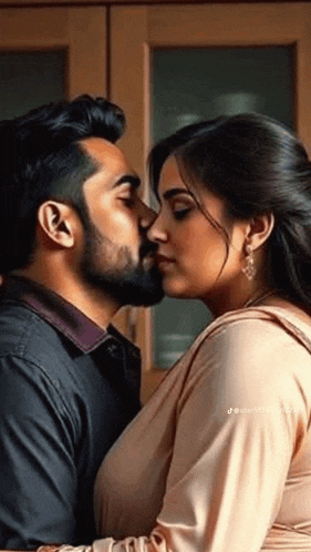 a man and a woman are kissing in front of a cabinet .