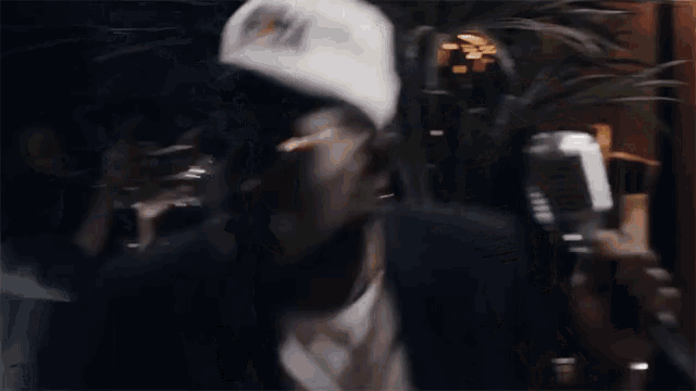 a man wearing a hat and sunglasses is singing into a microphone and the word wooo is on the bottom
