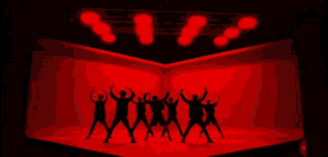 a group of people are dancing on a stage in a red room .