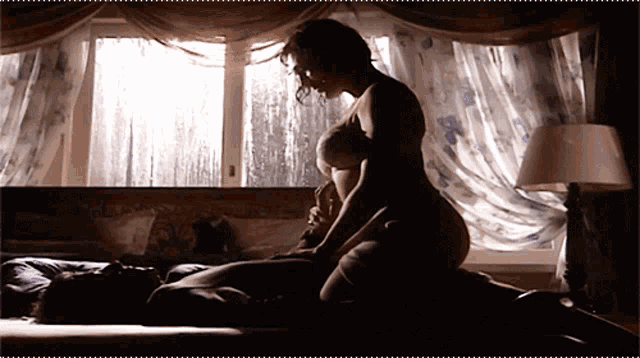 a woman in a bra is laying on top of a man in a bedroom