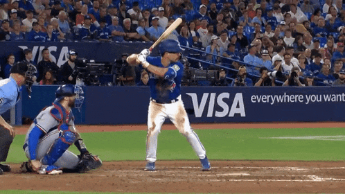 a baseball player getting ready to swing at a pitch with a visa ad behind him
