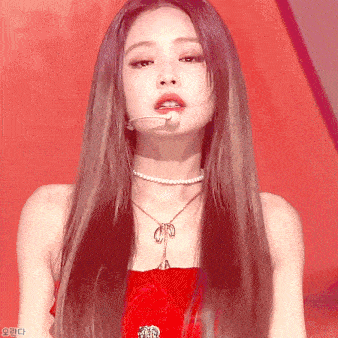 a woman with long hair is wearing a pearl necklace and a red dress