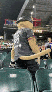 a mascot wearing a number 77 jersey is dancing in the stands
