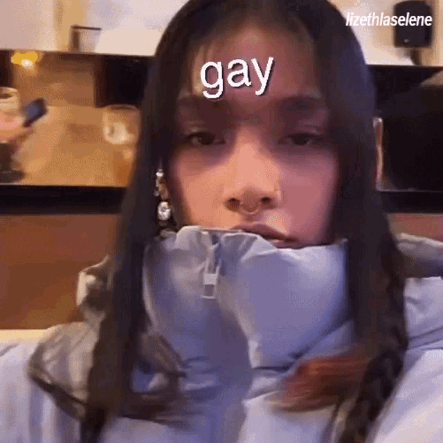 a woman wearing a jacket has the word gay on her forehead