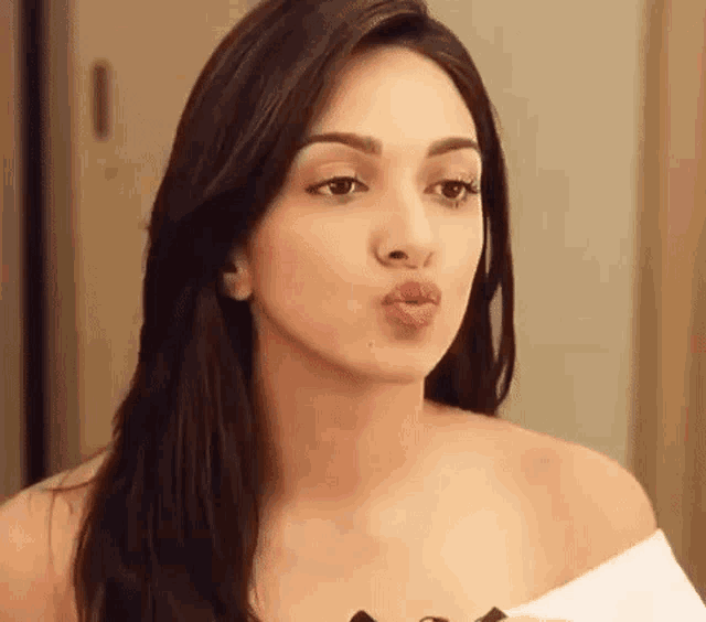 a woman is blowing a kiss at the camera while looking at herself in the mirror .