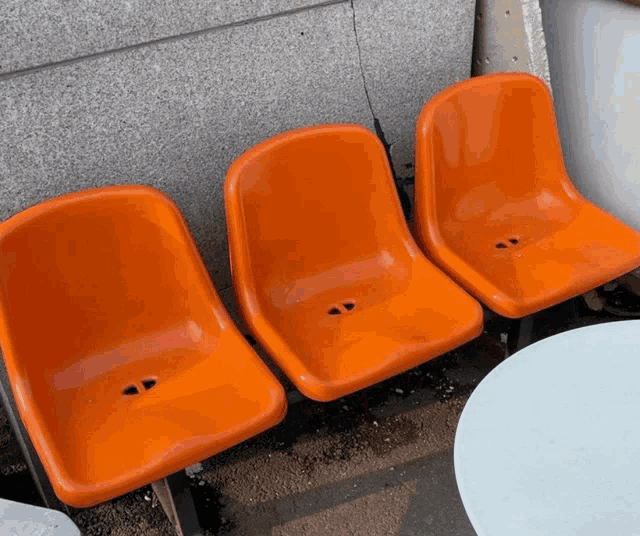 three orange chairs are lined up in a row