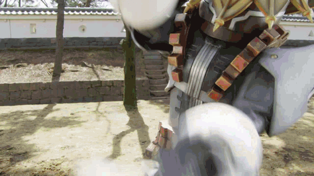 a robot is standing in the dirt in front of a brick wall