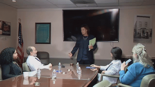 a group of people sitting around a conference table with a sign on the wall that says ' sidney smith '