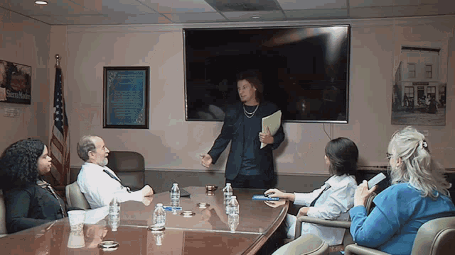a group of people sitting around a conference table with a sign on the wall that says ' sidney smith '