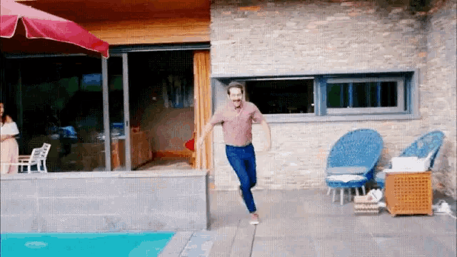 a man is jumping into a pool in front of a brick building