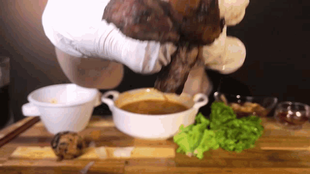 a person is pouring soup into a white bowl on a wooden table