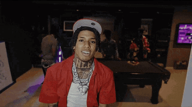 a man wearing a red jacket and a hat has a tattoo on his chest that says nlp