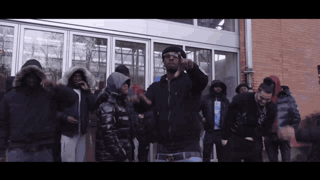 a group of people are standing in front of a building and one of them is wearing a hoodie that says ny on it