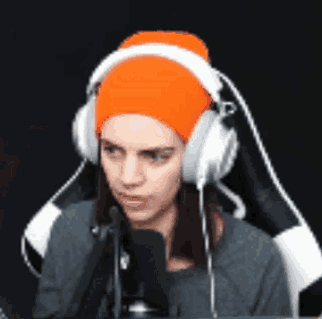 a woman wearing headphones and an orange beanie is sitting in a chair .