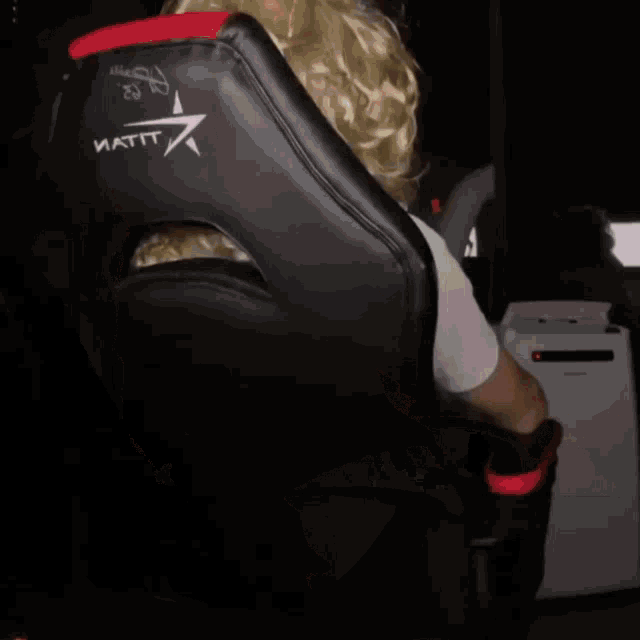 a woman wearing a blonde wig and sunglasses sits in a chair
