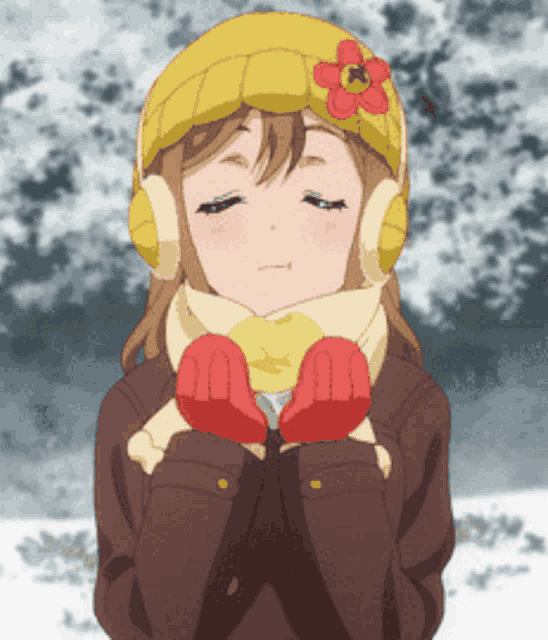 a girl wearing a yellow hat and scarf is holding her hands together in the snow