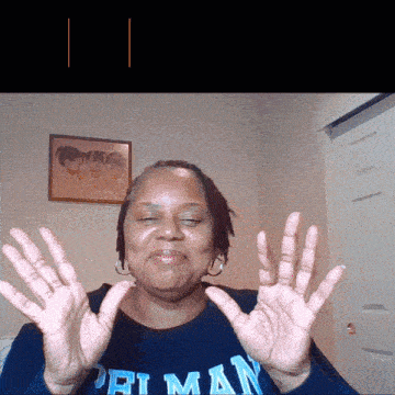 a woman wearing a shirt that says ' priman ' on it holds her hands up