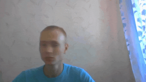 a blurry picture of a man in a blue shirt in front of a window