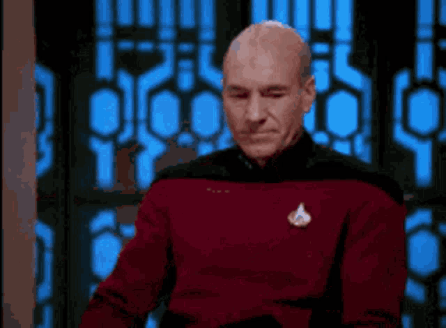 a man in a star trek uniform is sitting in front of a window .