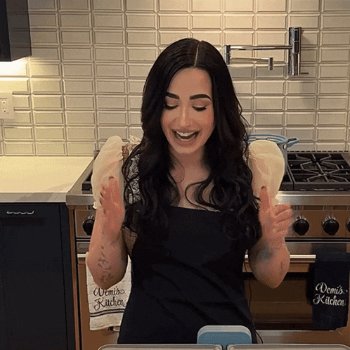 a woman in a kitchen with a towel that says " demi 's kitchen " on it