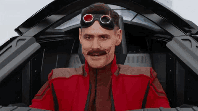 a man with a mustache and goggles is sitting in the cockpit of a car