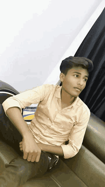 a young man is sitting on a couch with his hands on his hips