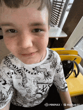 a boy wearing a shirt with dragons on it is sitting at a table