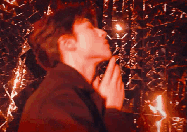 a man in a black jacket is praying in front of a mirror wall