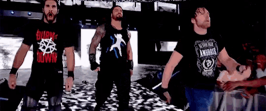 three wrestlers are standing next to each other on a stage in a wrestling ring .