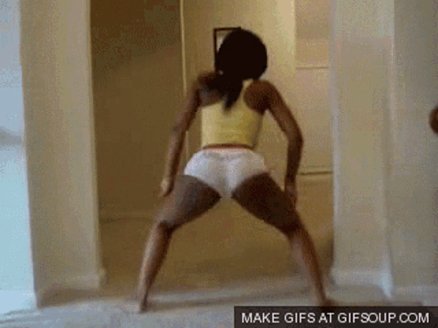 a woman in a yellow tank top and white shorts is dancing in a hallway with a gif soup.com watermark
