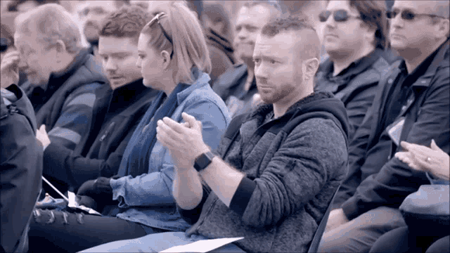 a group of people sitting in a row clapping