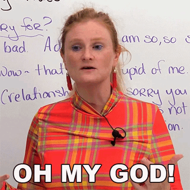 a woman in a plaid shirt says oh my god in front of a white board