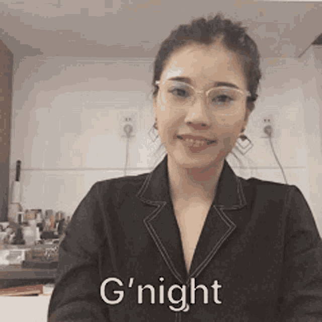 a woman wearing glasses and a black jacket says " g night "