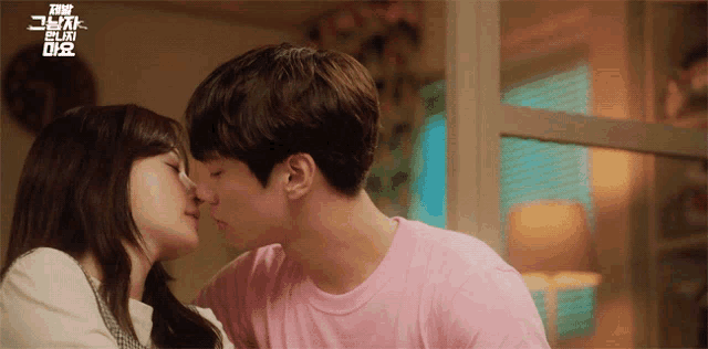 a man and a woman are kissing in front of a sign that says ' i love you '