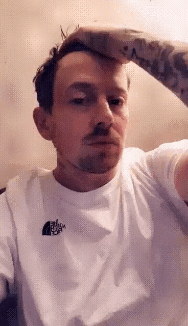 a man wearing a white shirt with the north face logo on it
