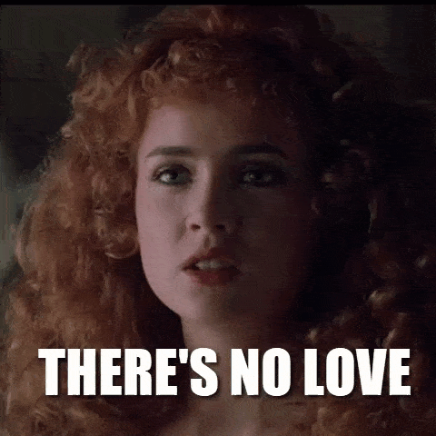 a woman with red hair is looking at the camera with the words `` there 's no love '' written above her .